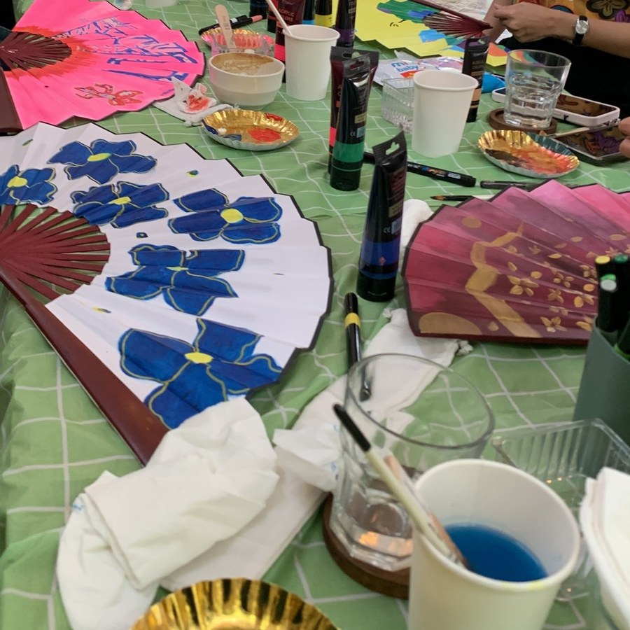 Fans painted by guests at our last session, drying on the table