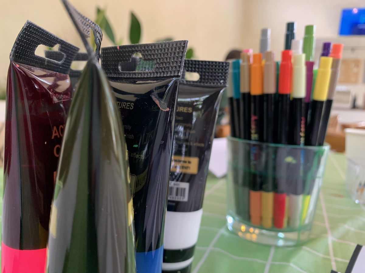 Acrylic paint tubes and a jar of markers on the table