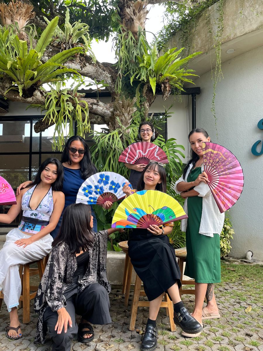 Group photo of guests holding their painted fans in the garden
